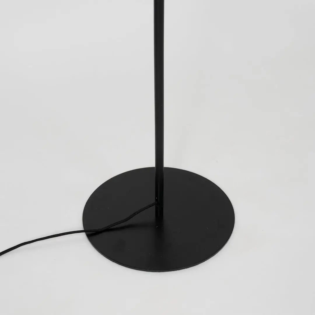 Modern floor lamp with black metal base and angled gold arm supporting matte black shade for reading or decor lighting.