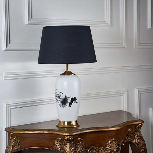 White ceramic table lamp with black floral detailing and navy fabric shade designed for refined decorative table lighting.