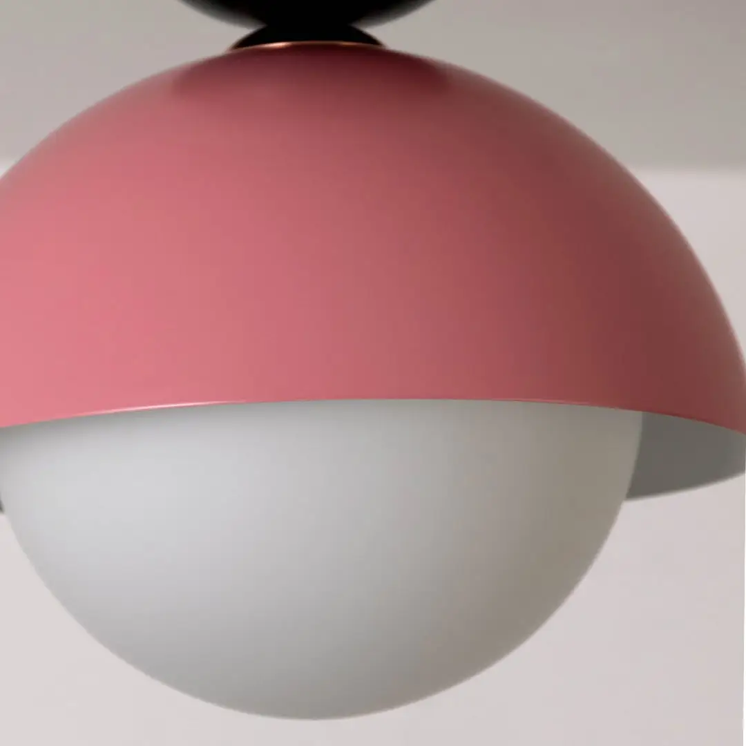 Closeup view of the pink dome ceiling light highlighting its smooth finish and simple round white globe design.