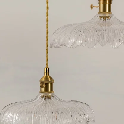 Closeup of clear patterned glass pendant light with polished gold fittings showcasing refined vintage craftsmanship.