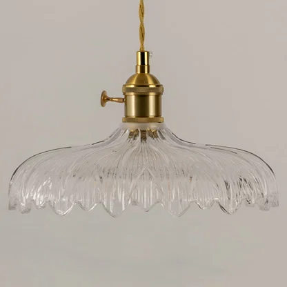 Closeup of clear textured glass pendant light with polished gold hardware showcasing premium craftsmanship.