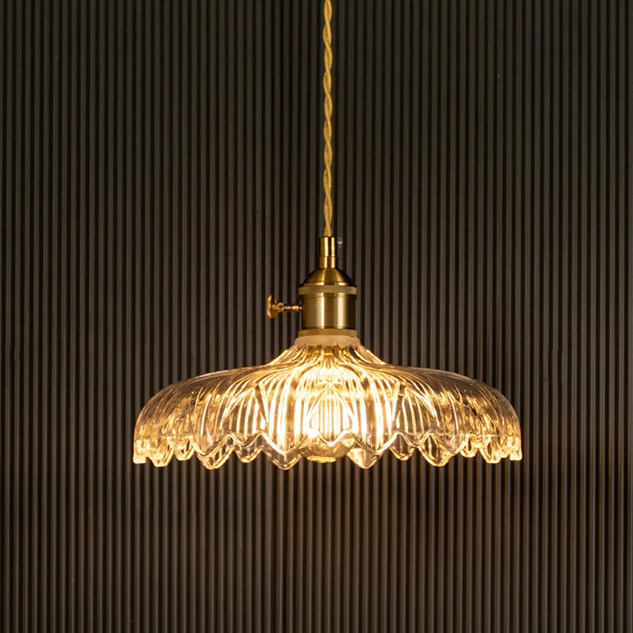 Crystal glass pendant light with brass frame illuminated for sophisticated ceiling decor.