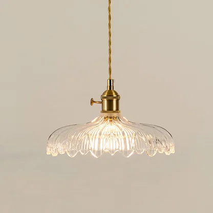 Illuminated clear patterned glass pendant light with gold fittings creating soft ambient lighting indoors.