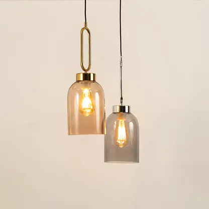 Amber and smoke glass pendant lights suspended above dining area adding warm modern decorative lighting elegance.