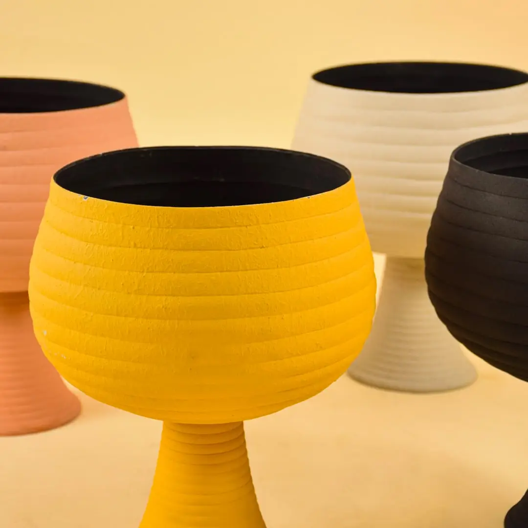 Closeup of cream metal pedestal bowl highlighting its textured finish and modern shape perfect for home styling accents.