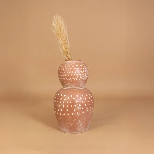 Decorative ceramic vase in pink finish with dried grass for table decor or shelf styling modern home placement neutral background.