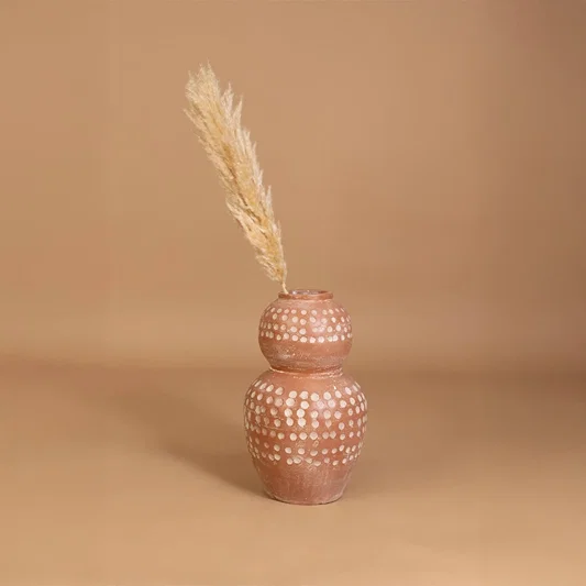 Brown terracotta decorative vase with white polka dots placed in a styled interior adding earthy artistic decor to shelves consoles and living spaces.
