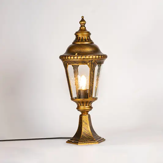 Antique gold outdoor gate light with glowing glass shade for luxury exterior decor styling use.