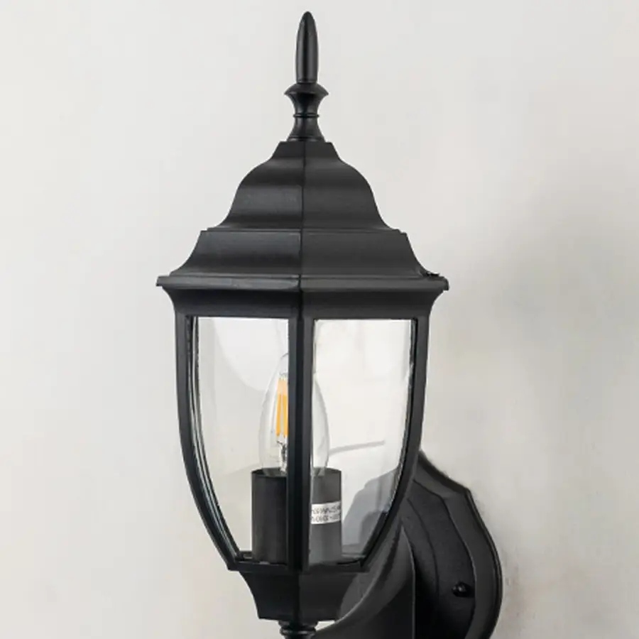 Closeup image of black metal outdoor wall light with clear glass shade for stylish exterior decor.
