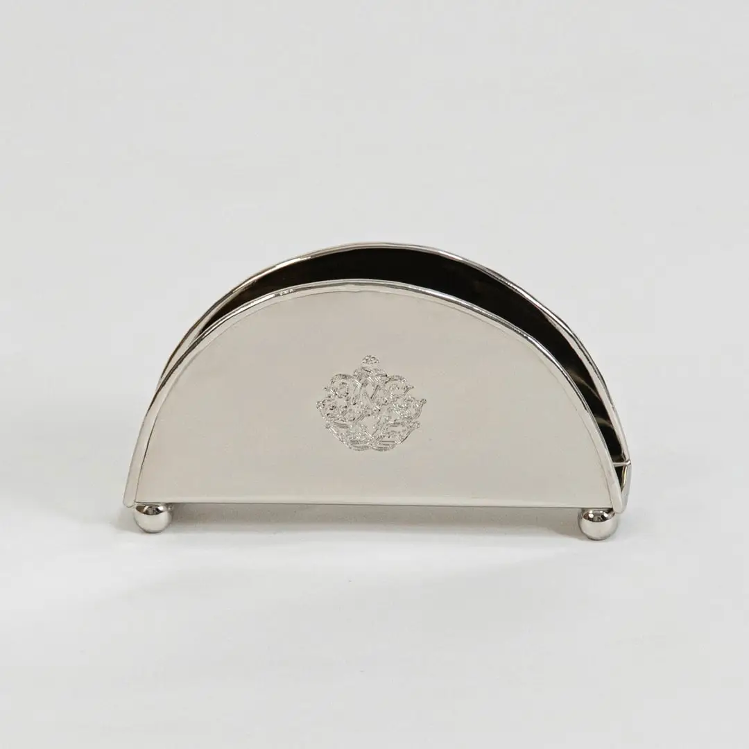 Half-round brass napkin holder with floral crest placed on white background showcasing finish and elegant shape.