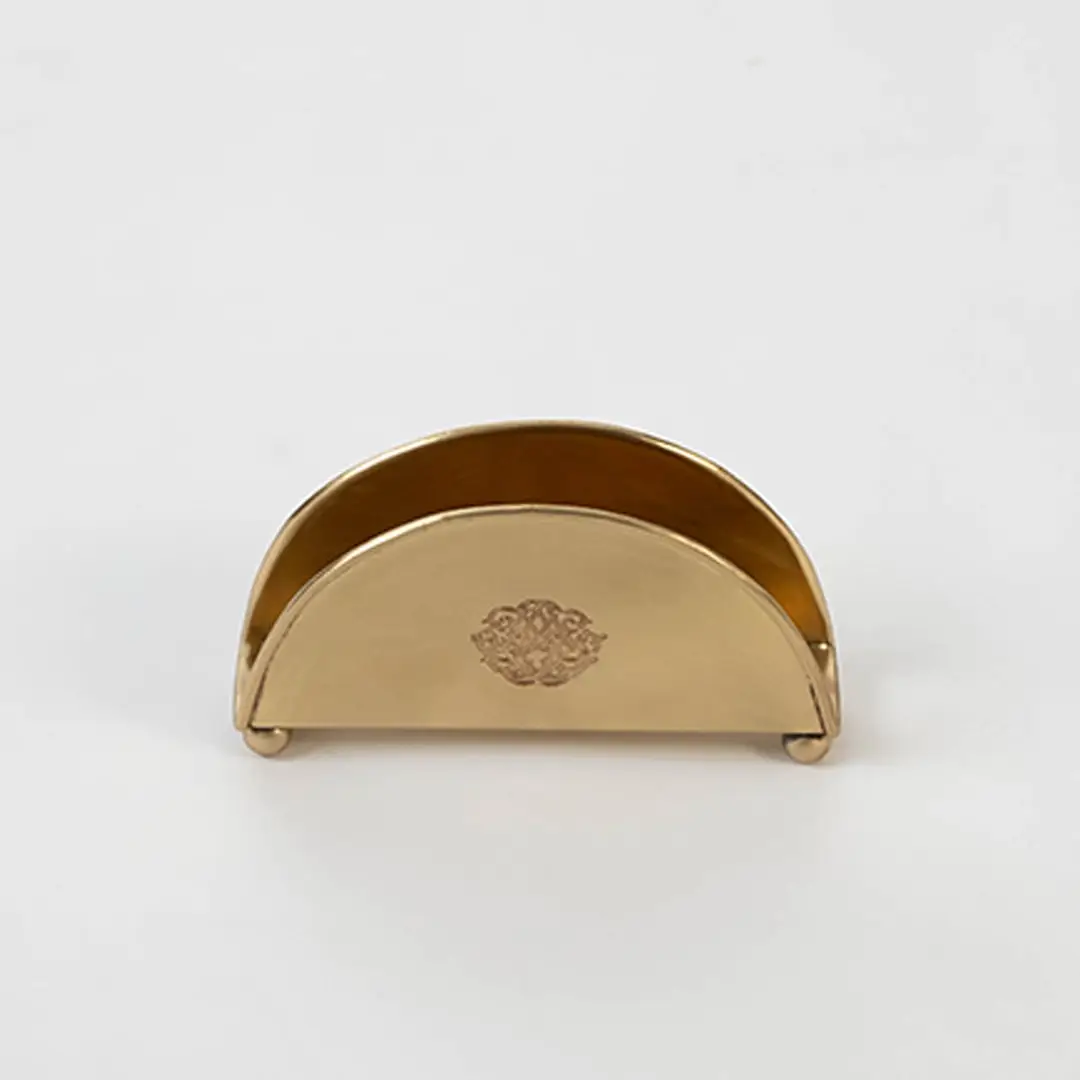 Half-round brass napkin holder with floral crest placed on white background showcasing finish and elegant shape.