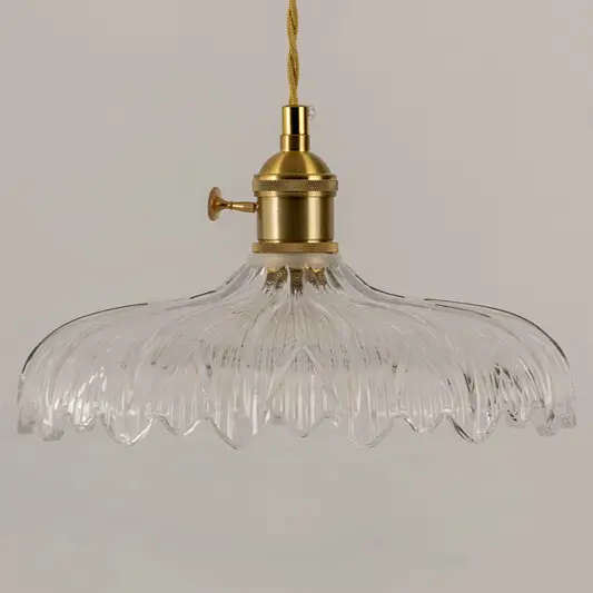Clear textured glass pendant light with gold metal fixture illuminated to showcase elegant decorative ceiling lighting.