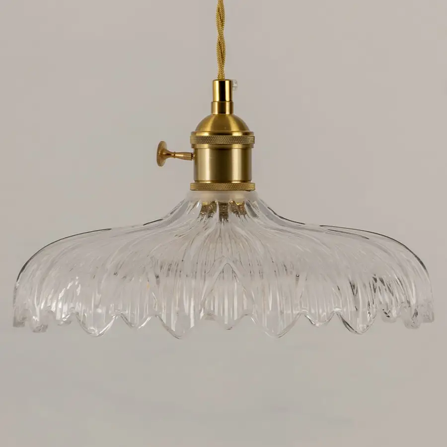 Clear textured glass pendant light with gold metal fixture illuminated to showcase elegant decorative ceiling lighting.