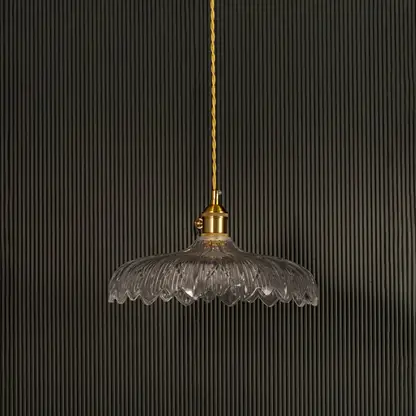 Clear ribbed glass pendant light with gold metal holder switched off on black background showcasing elegant vintage design.