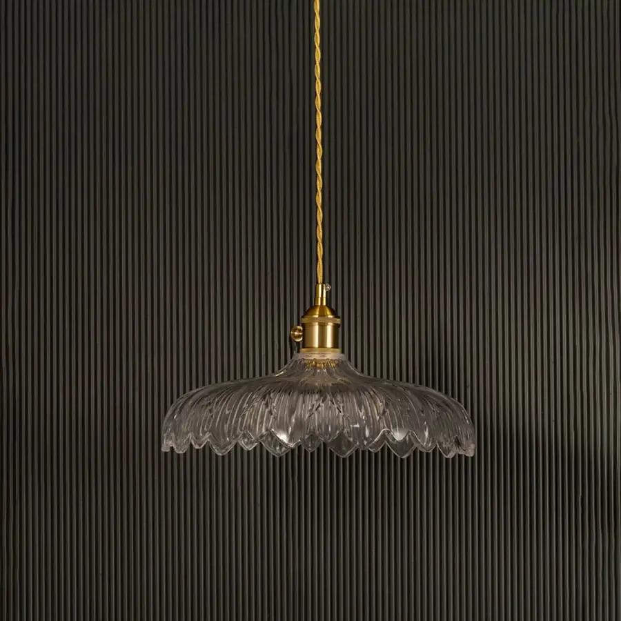 Clear ribbed glass pendant light with gold metal holder switched off on black background showcasing elegant vintage design.