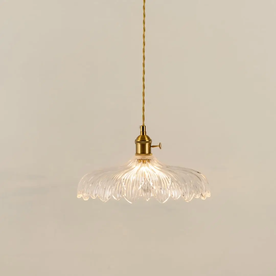 Gold metal pendant light with textured glass shade illuminated to showcase elegant decorative ceiling lighting appeal.