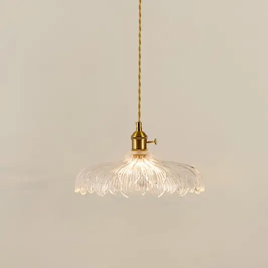 Gold metal pendant light with textured glass shade illuminated to showcase elegant decorative ceiling lighting appeal.