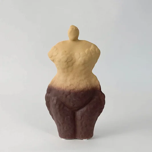 Abstract ceramic torso sculpture with dual tone beige and brown finish placed on white surface against neutral background showcasing modern artistic home decor styling.