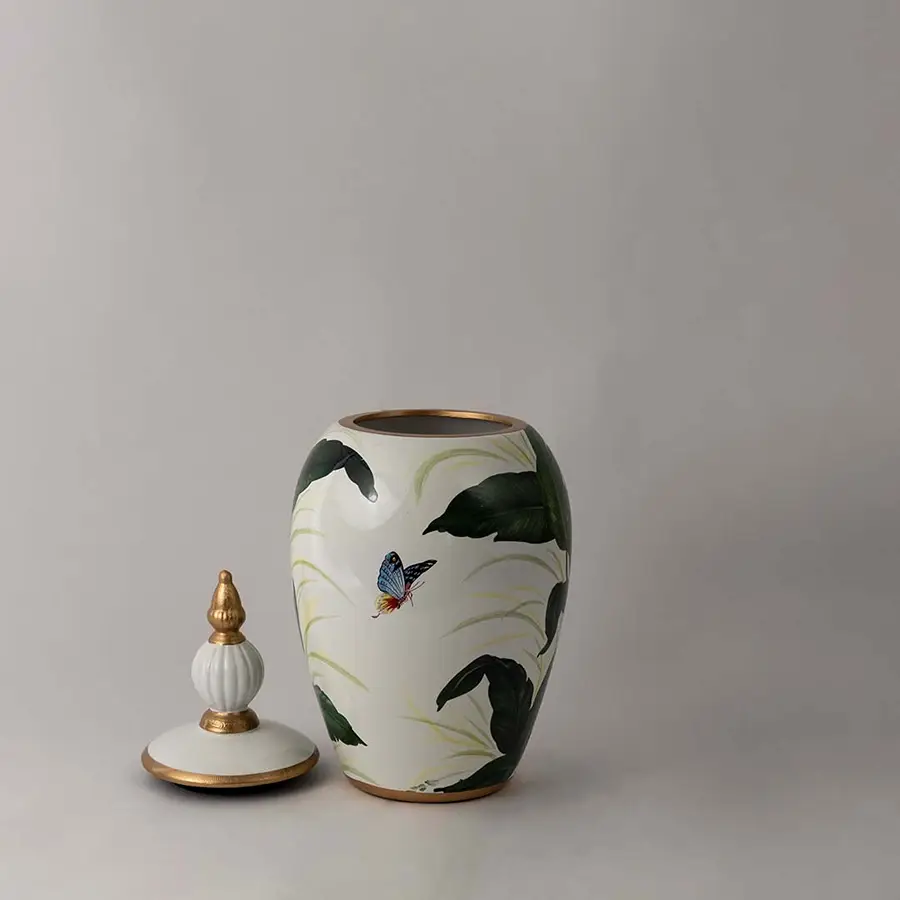 Stylish white ceramic decor jar with green botanical design and golden lid crafted for luxury home interior display.