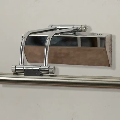 Closeup of chrome metal picture light showing polished finish slim bar design and warm directional illumination.