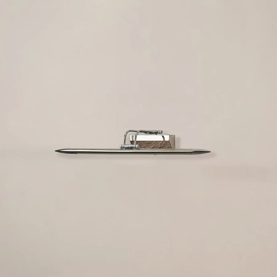 Chrome metal picture light on a white background with the light off highlighting its sleek modern reflective design.