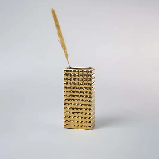 Modern gold textured vase placed in a minimal setting creating a bold metallic decor accent perfect for contemporary living spaces.