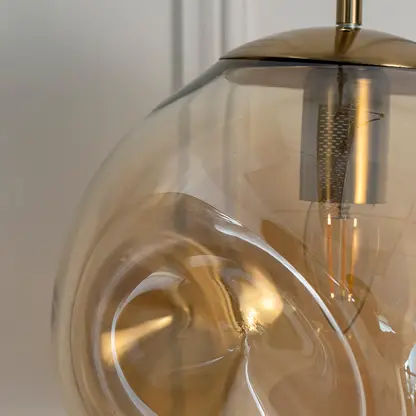Closeup of amber glass pendant light with black metal canopy showcasing artistic curves and fine details.