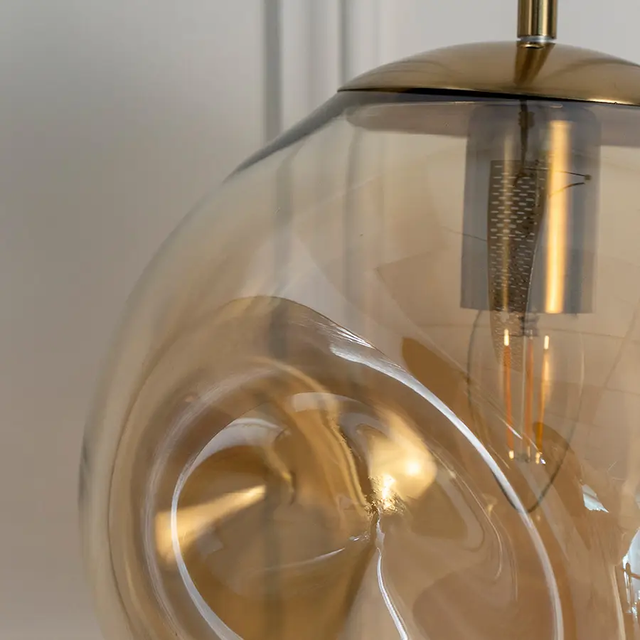 Closeup of amber glass pendant light with black metal canopy showcasing artistic curves and fine details.