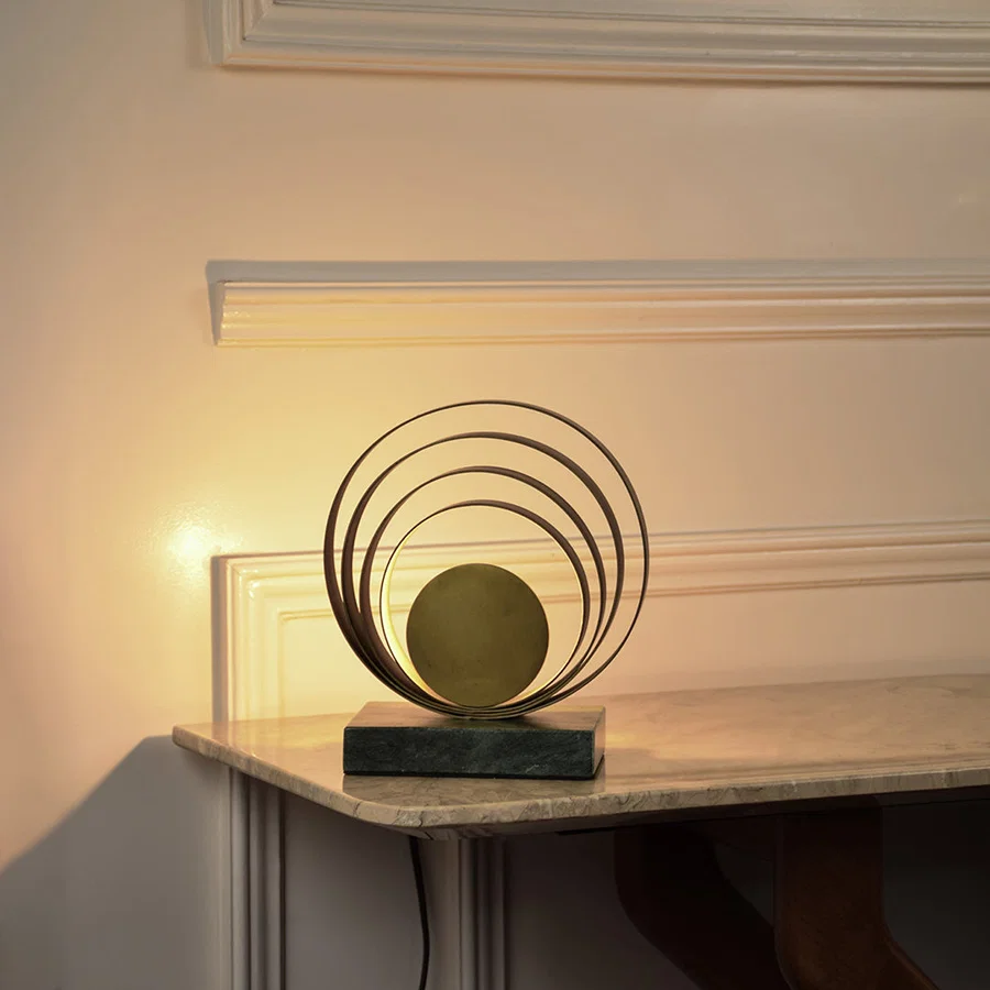 Modern sculptural table lamp with concentric metal rings casting warm ambient light for stylish interior decor.