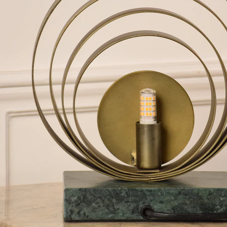 Closeup of circular brass ring table lamp showcasing fine metal texture and sleek marble base designed for high-end interior styling.