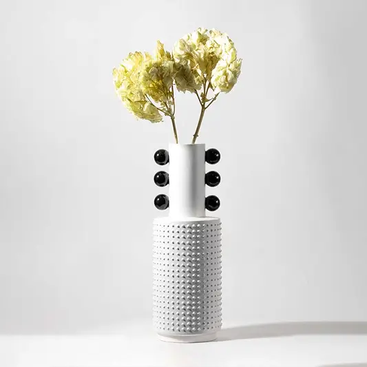 Modern ceramic vase in white with black ball design styled with artificial green hydrangea flower for elegant home decor.