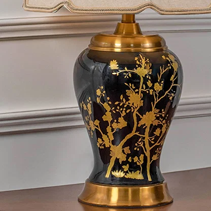 Closeup of black and gold ceramic table lamp showing detailed floral patterns gold accents and fabric shade emphasizing luxury handcrafted design.