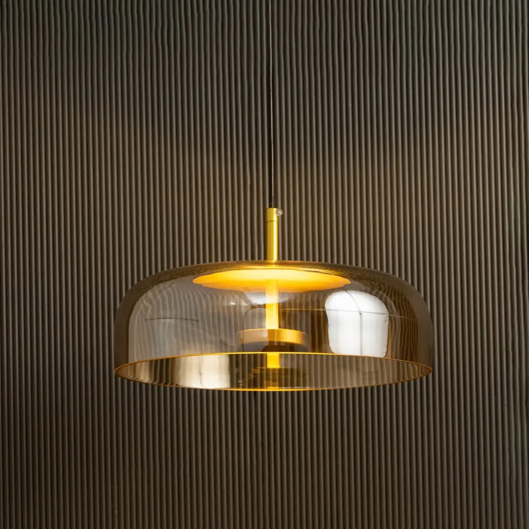 Amber glass pendant light with metal detailing casting a warm ambient glow imagined against a dark background creating a dramatic modern interior decor mood.