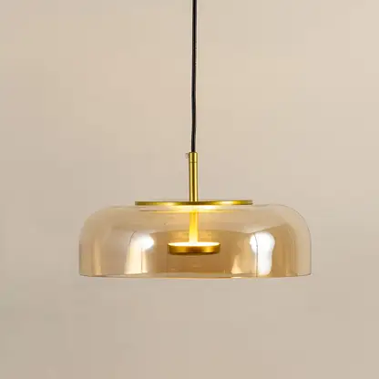 Amber glass pendant light with gold metal fixture illuminated to display luxury decorative ceiling lighting elegance.