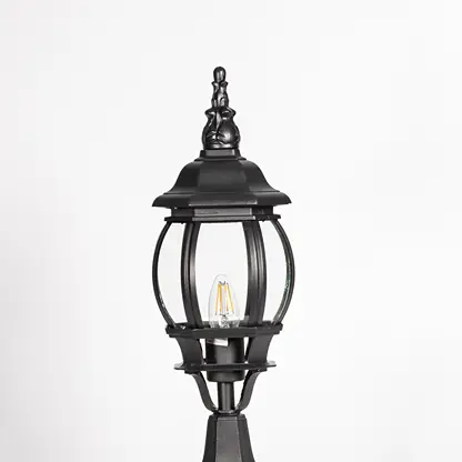 Closeup of decorative tall outdoor black pillar lamp with curved round glass panels and LED bulb showing vintage style.