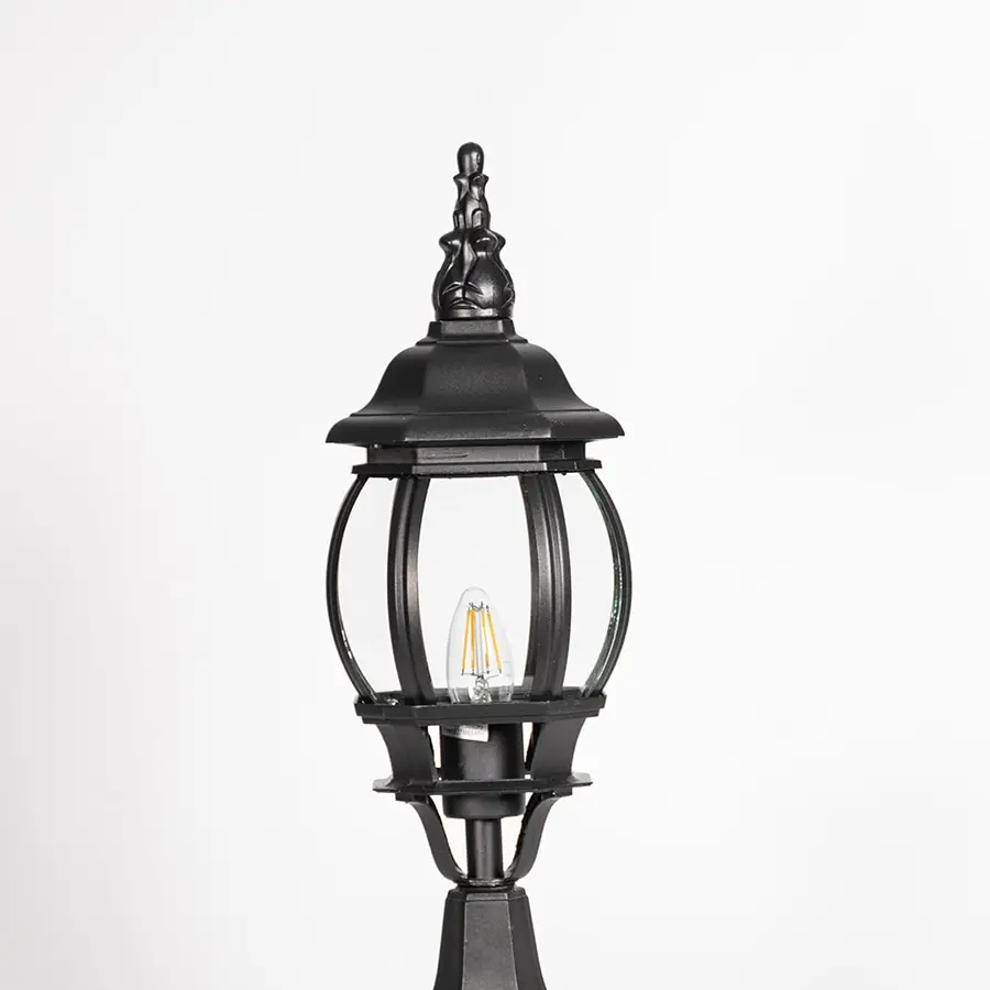 Closeup of decorative tall outdoor black pillar lamp with curved round glass panels and LED bulb showing vintage style.