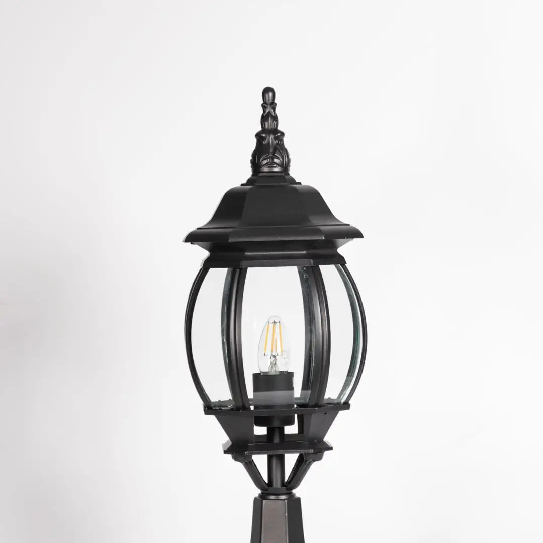 Closeup of decorative outdoor black pillar light with clear curved glass and LED bulb highlighting premium classic design.