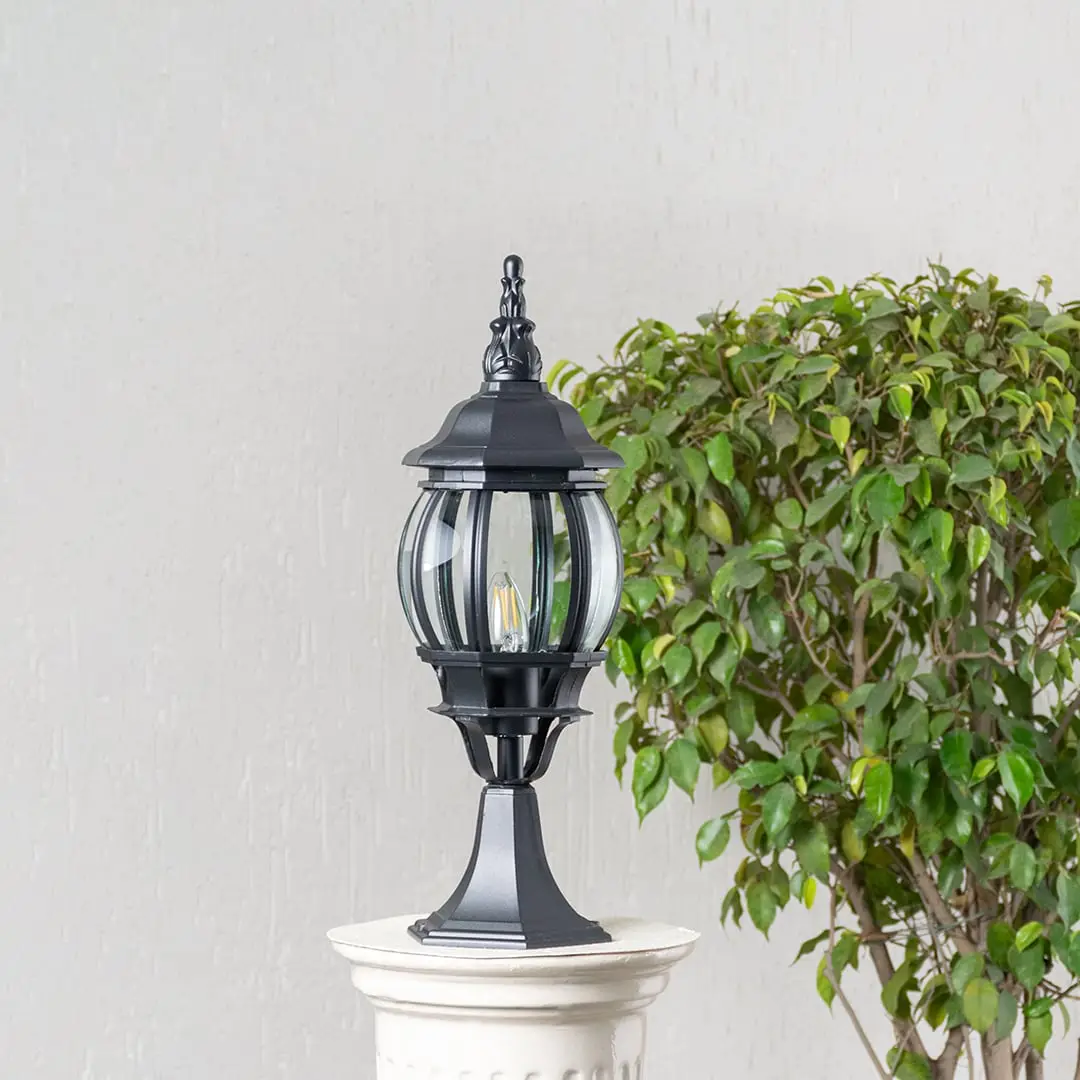 Classic black outdoor pillar lamp with curved glass panels placed on stone pillar ideal for villa entrance and garden decor.