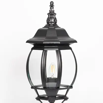 Closeup of decorative black pillar light with curved glass panels and LED bulb showcasing elegant outdoor lighting.