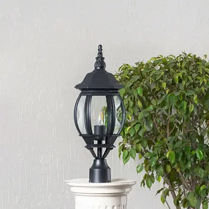 Classic black outdoor pillar lamp with clear curved glass shade placed on stone pillar ideal for entrance and garden.