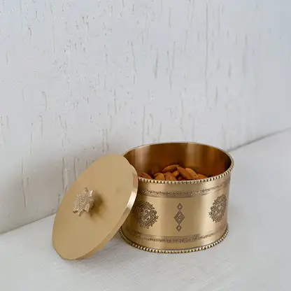 Gold metal storage jar with engraved design presented inside a black gift box with lid open for packaging display.