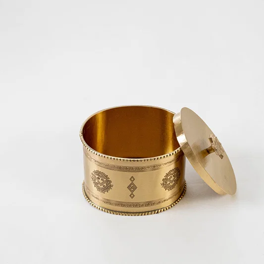 Elegant metal storage box in gold finish with lid for dining table or decor accessory placement white background.