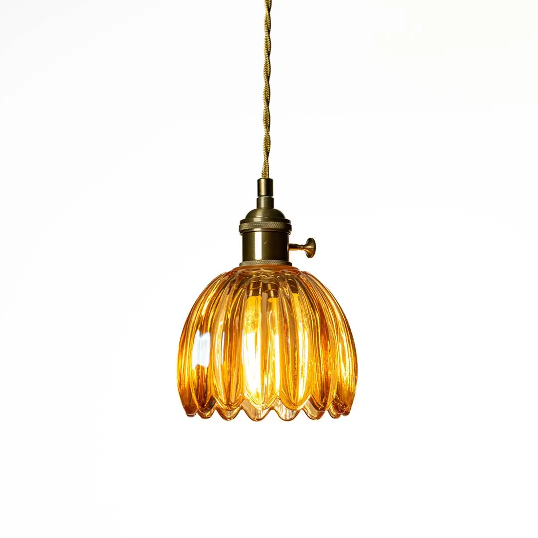 Amber ribbed glass pendant light with antique brass accents creating cozy illumination indoors.