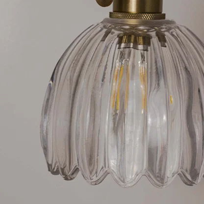 Clear ribbed glass pendant light with gold fixture placed against neutral wall background closeup highlighting elegant vintage inspired lighting decor styling.