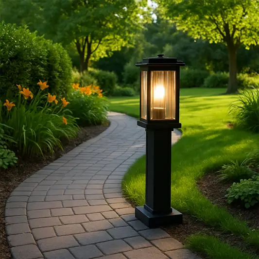 A modern outdoor bollard light glowing warmly along a curved garden pathway surrounded by lush greenery and vibrant flowers creating an inviting and elegant evening ambiance.