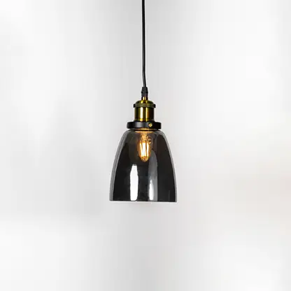 Smoked glass pendant light illuminated with warm glow and brass metal accents for modern ceiling lighting decor.