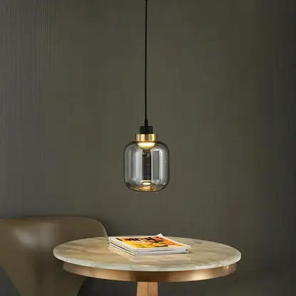Smoky glass pendant light with warm glow adding sophisticated charm to dining room settings.