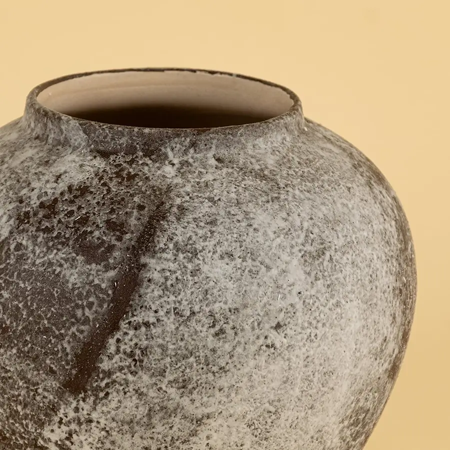 Detailed view of handcrafted ceramic vase with rustic grey brown texture and artistic round body design.