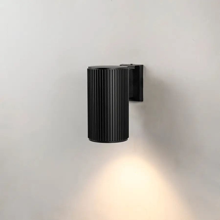 Black metal outdoor wall light on white background with ribbed texture and downward glow for exterior decor.