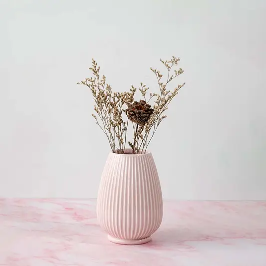 Stylish pink ceramic vase enhancing modern living room decor adding a soft pastel accent to the neutral setting.